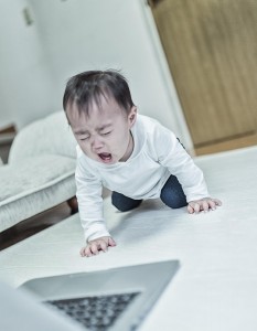 パソコンを前に泣く赤ちゃん